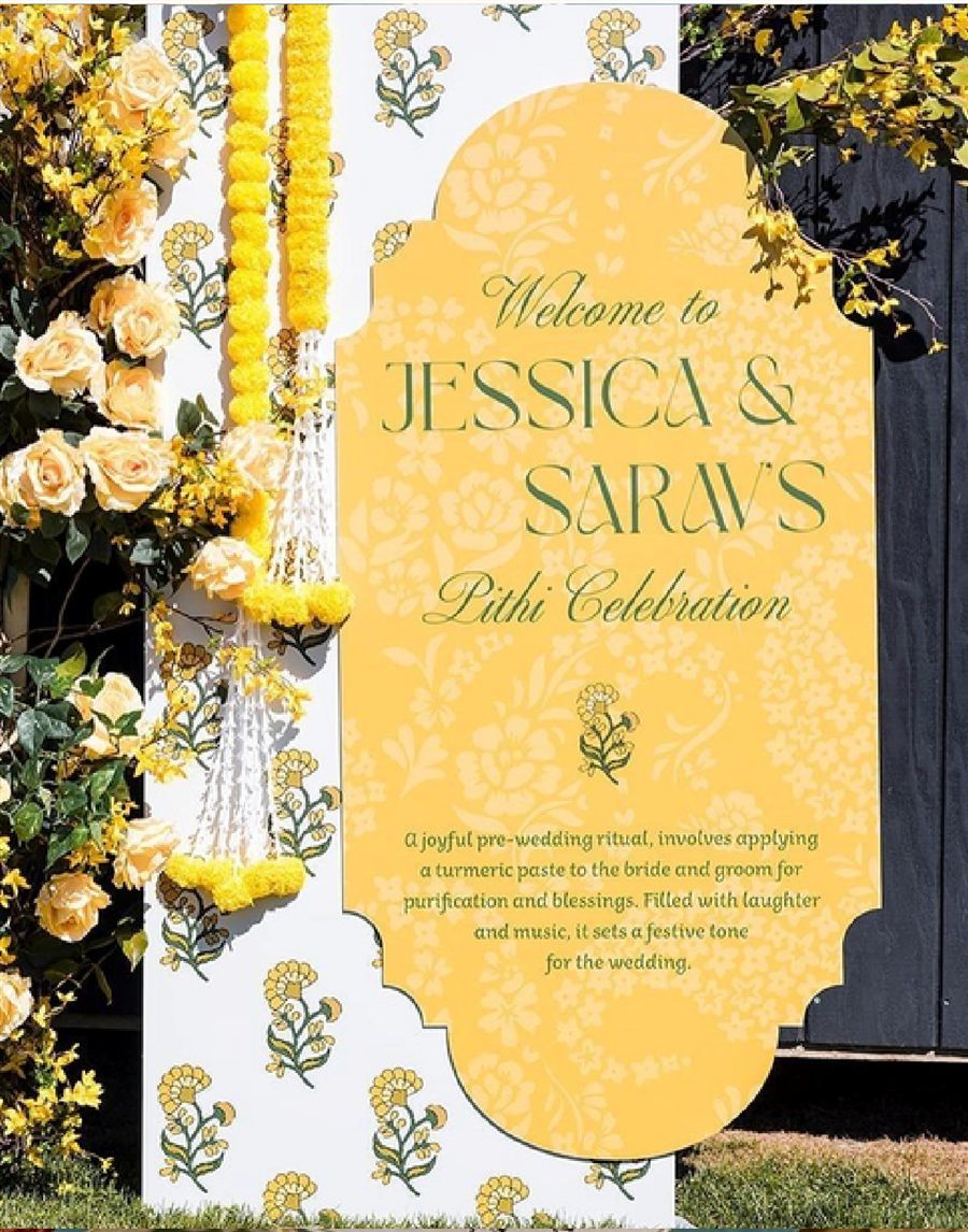 Yellow floral welcome board for a Pithi celebration, framed by marigold garlands